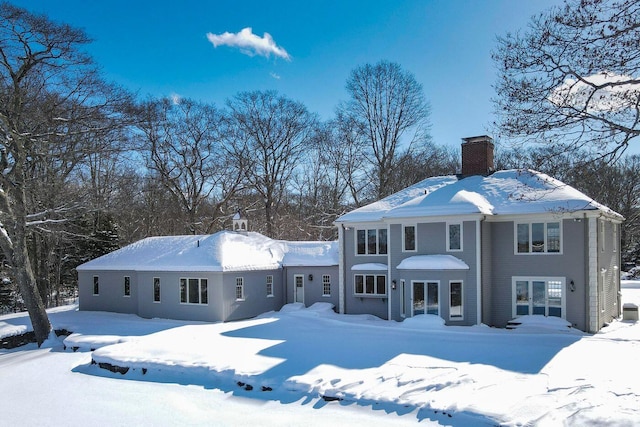 snow covered property featuring french doors and a chimney