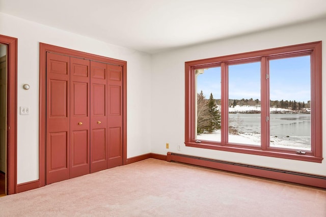 unfurnished bedroom featuring carpet floors, a baseboard radiator, a closet, and baseboards