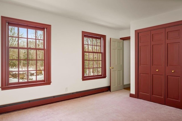 unfurnished bedroom featuring a closet, multiple windows, baseboard heating, and carpet flooring