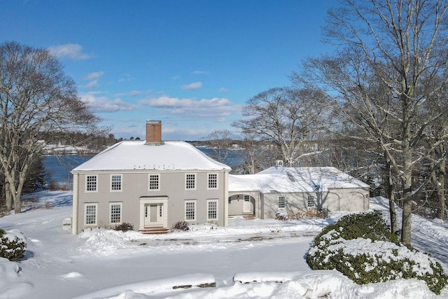 snow covered back of property featuring a chimney