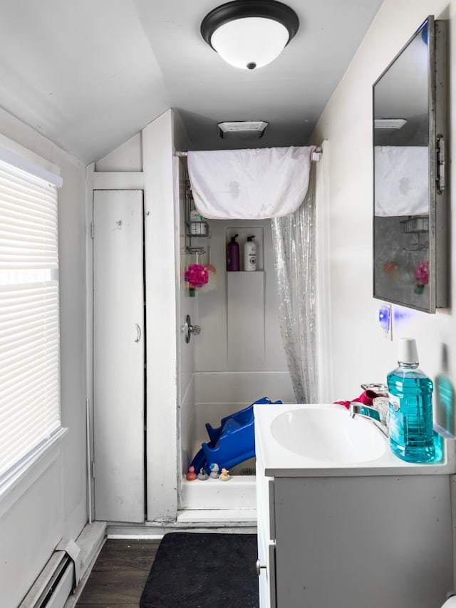 bathroom featuring hardwood / wood-style flooring, vanity, lofted ceiling, and baseboard heating