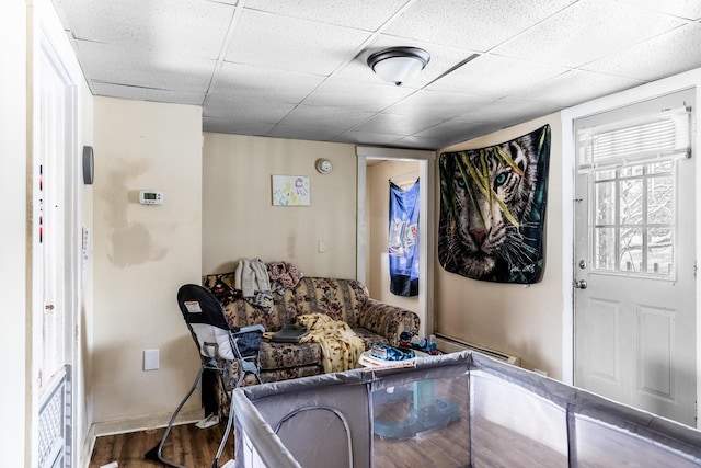 living room with baseboard heating, wood-type flooring, and a drop ceiling