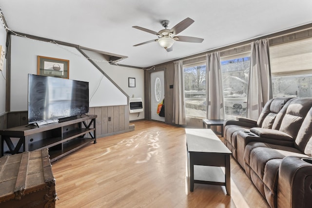 living room with heating unit, ceiling fan, and light hardwood / wood-style flooring