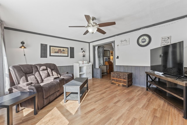 living room featuring crown molding, ceiling fan, and light wood-type flooring