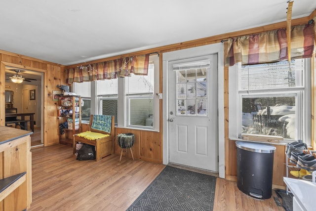 interior space featuring hardwood / wood-style flooring, ceiling fan, and wood walls