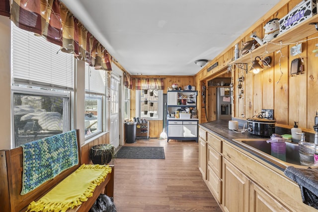 kitchen with wood walls, sink, stainless steel fridge, dark hardwood / wood-style flooring, and light brown cabinets