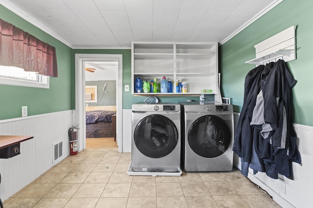 laundry room featuring crown molding, washer and clothes dryer, and light tile patterned floors