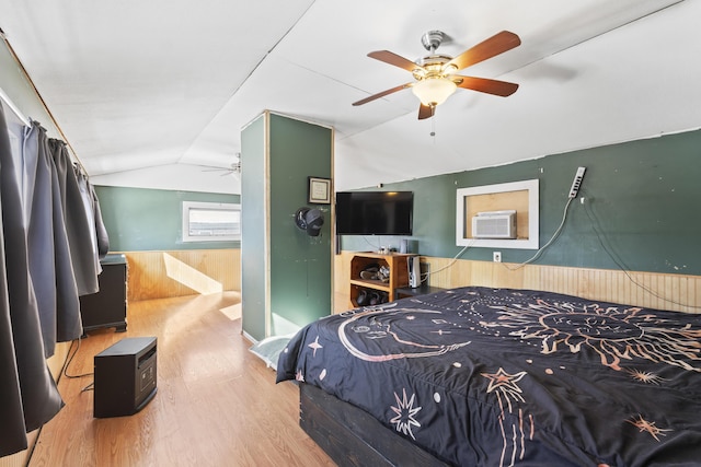 bedroom featuring lofted ceiling, hardwood / wood-style flooring, wooden walls, and ceiling fan