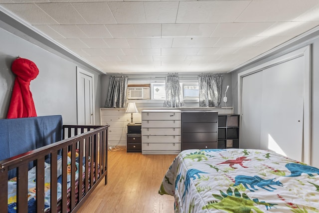 bedroom featuring a wall mounted air conditioner, a closet, and light wood-type flooring