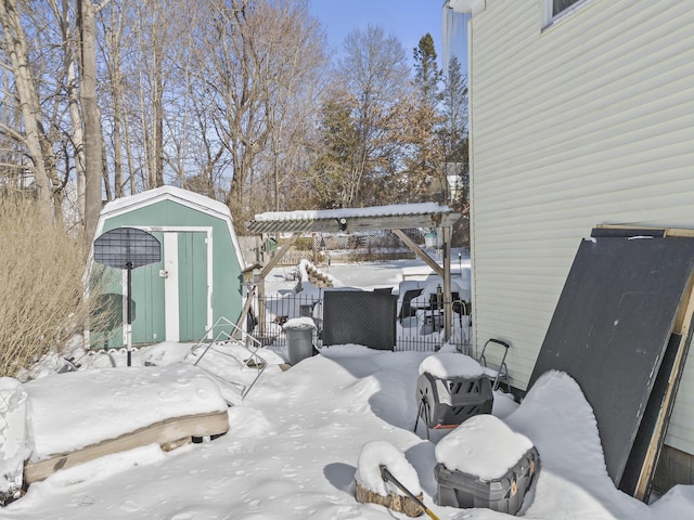 snow covered patio with a storage shed and a pergola