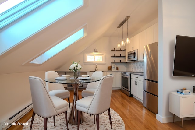 dining room featuring light wood-type flooring, lofted ceiling with skylight, and baseboard heating