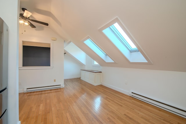 bonus room featuring a baseboard heating unit, light hardwood / wood-style floors, and vaulted ceiling with skylight