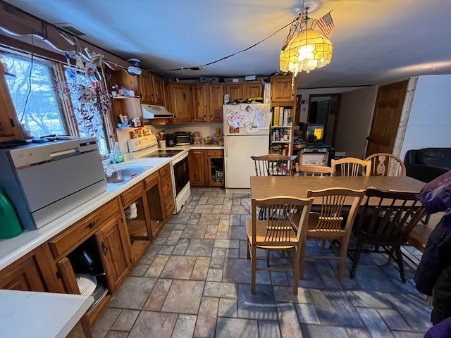 kitchen with white appliances, brown cabinets, stone finish flooring, light countertops, and under cabinet range hood