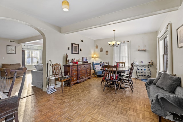 dining room featuring arched walkways, beamed ceiling, a chandelier, and visible vents