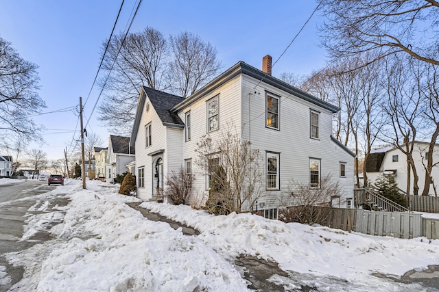 snow covered property with a chimney