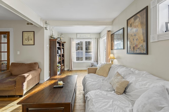 living room featuring beamed ceiling, visible vents, and baseboards