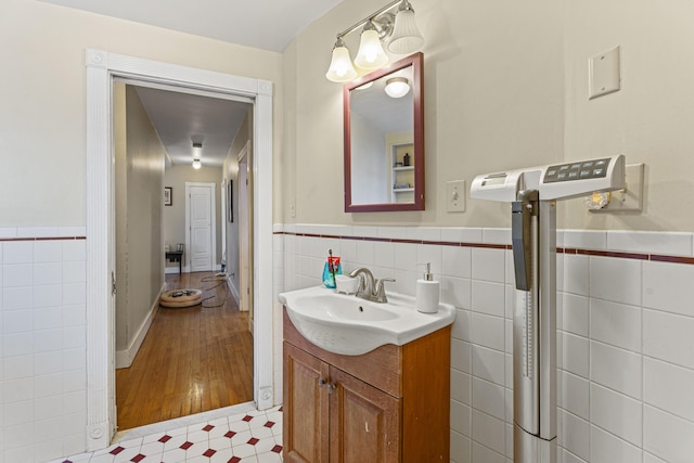 bathroom featuring a wainscoted wall, tile patterned floors, tile walls, and vanity