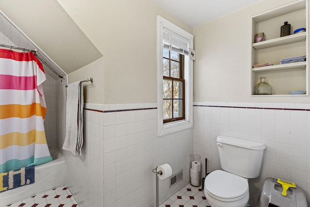 bathroom with toilet, tile walls, visible vents, and shower / tub combo with curtain