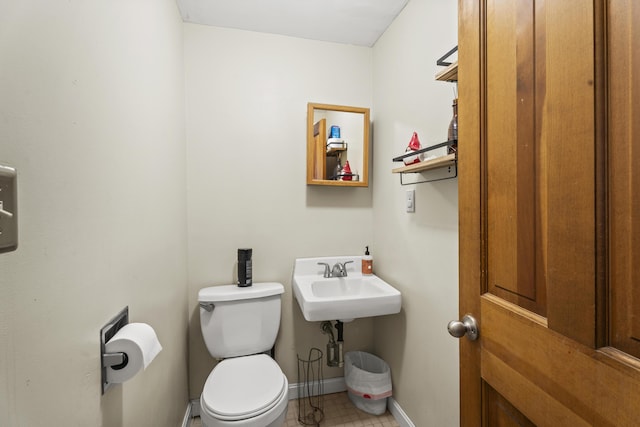 half bath with baseboards, a sink, and toilet