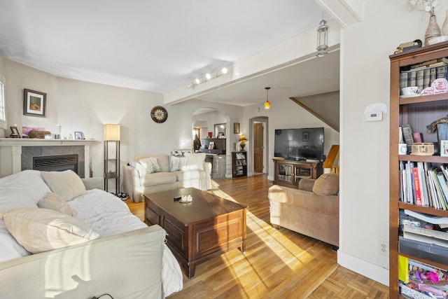 living area with parquet floors, arched walkways, and a tile fireplace