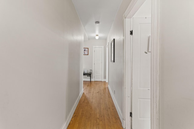 hallway with light wood-type flooring and baseboards