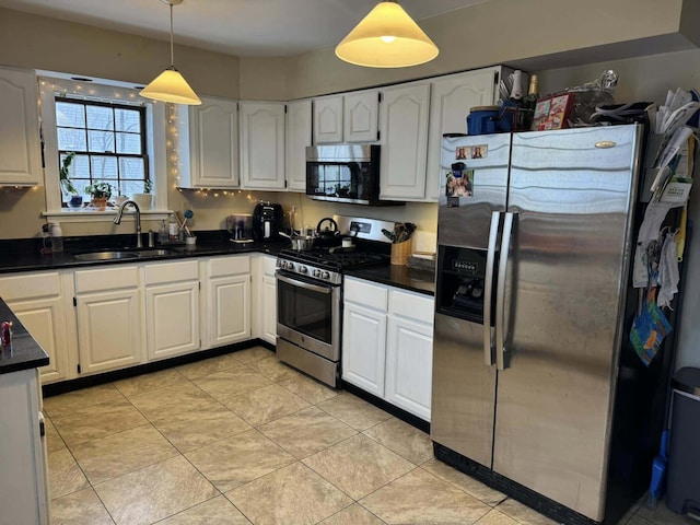 kitchen featuring dark countertops, white cabinetry, stainless steel appliances, and a sink