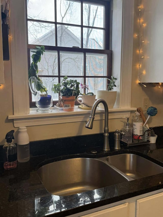 details with dark stone counters, white cabinets, and a sink