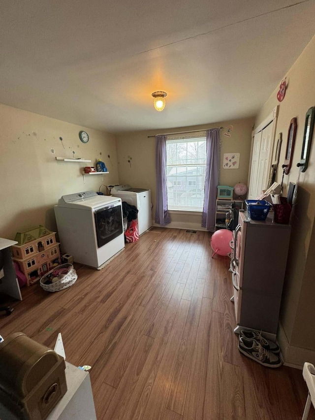 clothes washing area featuring laundry area, washer and clothes dryer, and wood finished floors