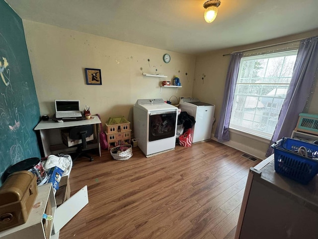 washroom featuring laundry area, independent washer and dryer, wood finished floors, and a healthy amount of sunlight