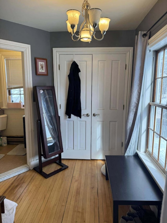 entrance foyer with light wood-style flooring, a baseboard heating unit, and a notable chandelier