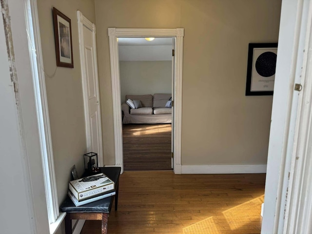 corridor with baseboards and wood finished floors