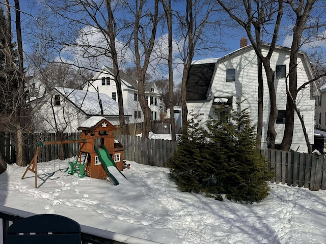 snow covered playground with fence and a playground