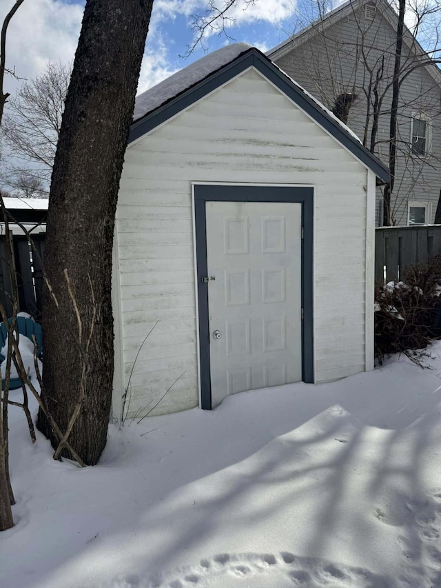 snow covered structure with an outbuilding