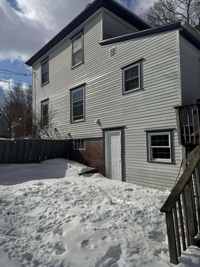 snow covered rear of property with brick siding