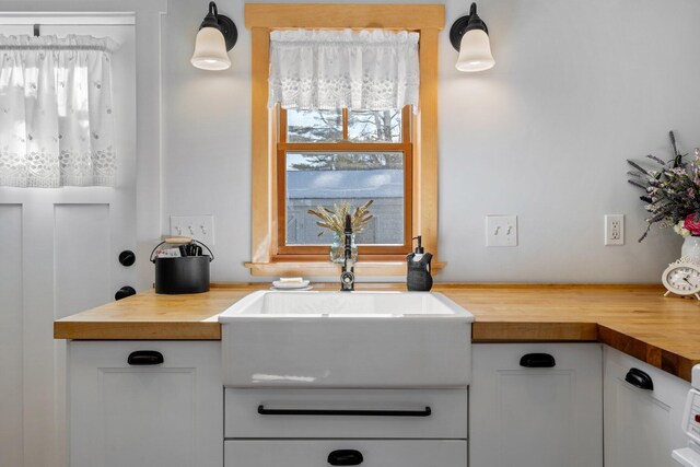 kitchen featuring decorative light fixtures, wooden counters, and white cabinets