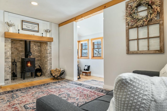 living room featuring a wood stove, hardwood / wood-style floors, and vaulted ceiling with beams