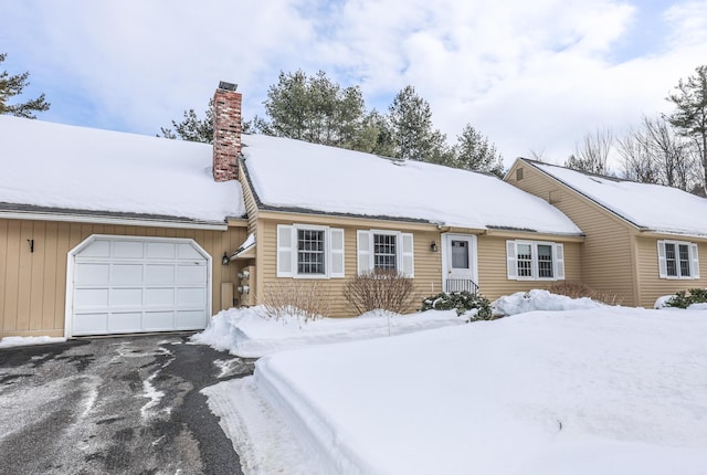 ranch-style house with an attached garage, a chimney, and aphalt driveway