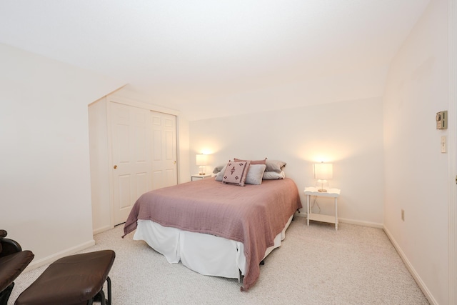 bedroom with a closet, light colored carpet, and baseboards