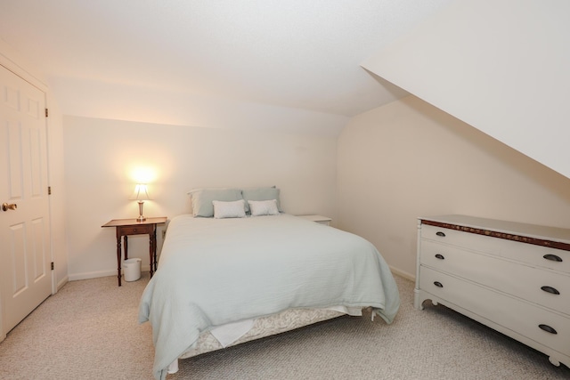 bedroom featuring light carpet, vaulted ceiling, and baseboards