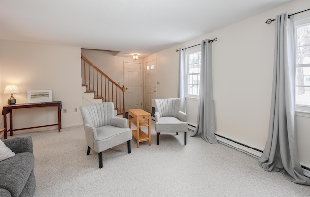 carpeted living area with a baseboard heating unit and stairway