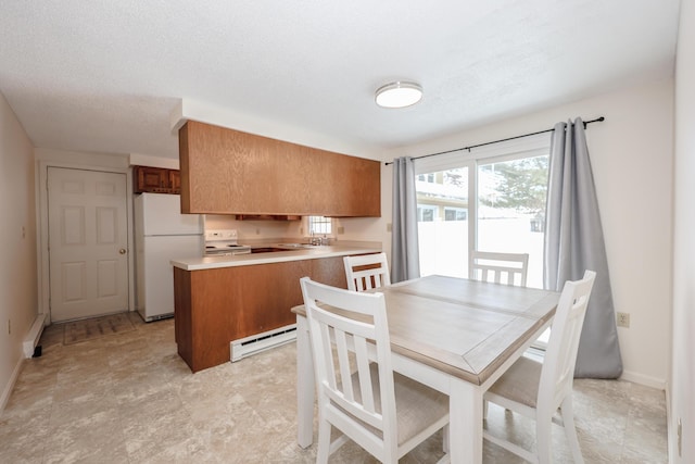 kitchen with brown cabinets, light countertops, baseboard heating, a sink, and white appliances