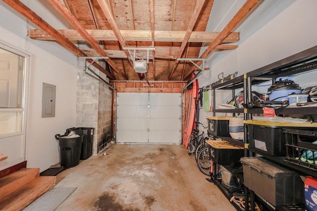 garage with concrete block wall, electric panel, and a garage door opener