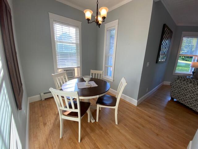 98 Fountain St, Bangor, ME 04401 - dining room featuring cooling unit, light hardwood / wood-style floors, baseboard heating, crown molding, and an inviting chandelier