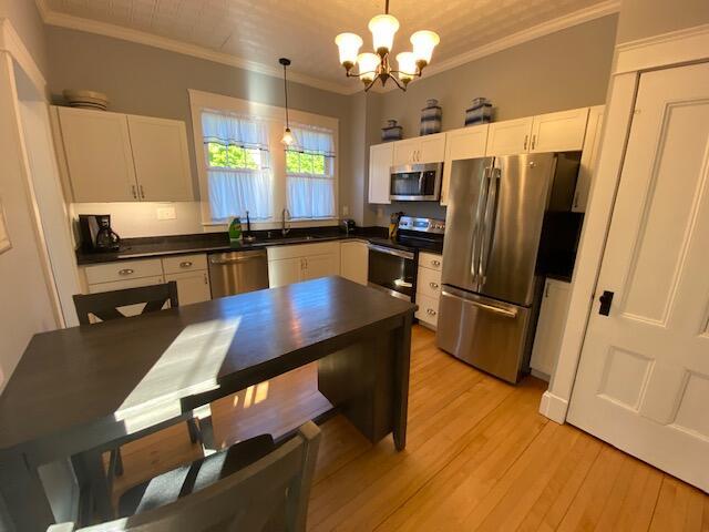 98 Fountain St, Bangor, ME 04401 - kitchen featuring white cabinetry, ornamental molding, appliances with stainless steel finishes, and decorative light fixtures