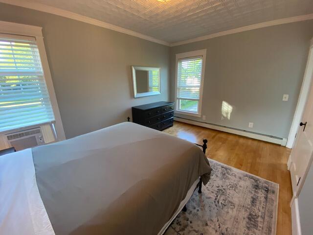 98 Fountain St, Bangor, ME 04401 - bedroom featuring baseboard heating, crown molding, hardwood / wood-style floors, and cooling unit