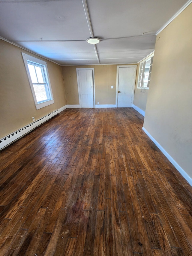 spare room with a baseboard heating unit, ornamental molding, and dark hardwood / wood-style floors