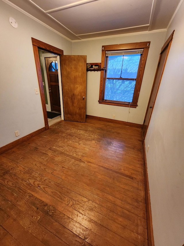 empty room with crown molding and wood-type flooring