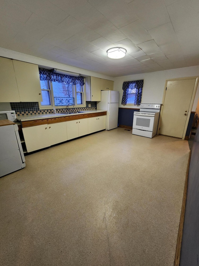 kitchen featuring sink, backsplash, and white appliances