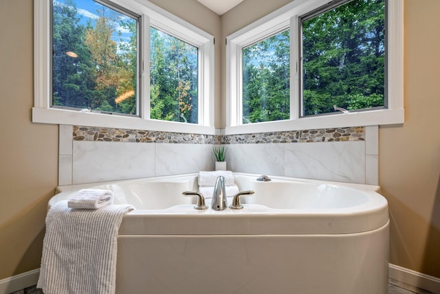 bathroom featuring tiled bath and a wealth of natural light