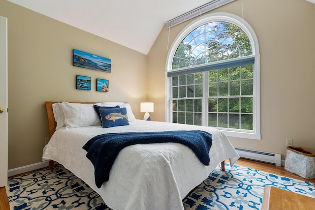 bedroom featuring multiple windows, vaulted ceiling, a baseboard heating unit, and hardwood / wood-style floors